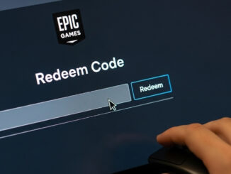 Una mano pronta a digitare un codice di riscatto su una tastiera, con lo schermo di un computer che mostra la pagina dedicata sul sito di Epic Games.